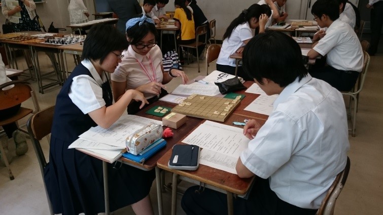 (IMG)将棋で、留学生と授業バディの生徒が英語で次の一手を相談